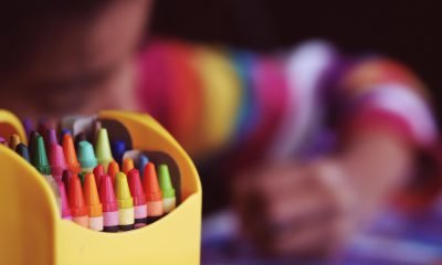 Bunte Stifte mit malendem Kind im Hintergrund