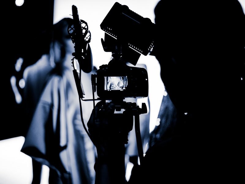 schwarzweiß-Aufnahme eines Mannes mit einer Filmkamera