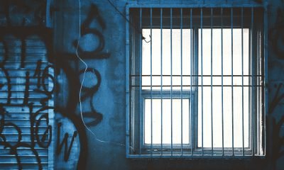 vergittertes Fenster vor Graffiti-Wand im Gefängnis