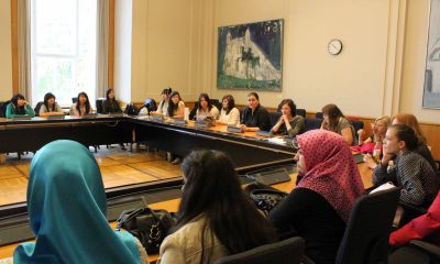 Das Bild zeigt Mädchen, die in einem Sitzungssaal im Kreis sitzen und einige grüne Abgeordnete.