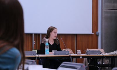 Das Bild zeigt ein Mädchen an einem Sitzungstisch, das redet.