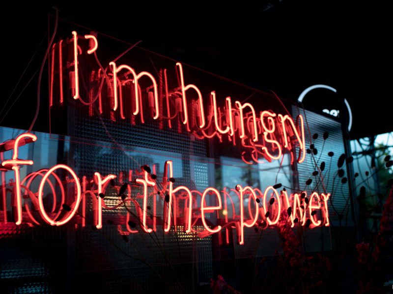 Auf dem Bild ist Leuchtschrift mit dem Schriftzug "I'm hungry for the power" zu sehen.