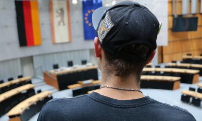 Auf dem Bild ist ein junger Mann von hinten zu sehen, der auf der Besuchertribüne des Plenarsaals im Berliner Abgeordnetenhaus steht.