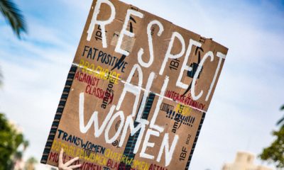 Es ist eine Frau auf einer Demonstration zu sehen, die ein Schild mit der Aufschrift "Respect all women" hoch hält.