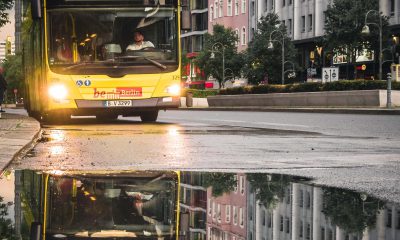 Ein Bus fährt auf der Straße und spiegelt sich in einer Pfütze