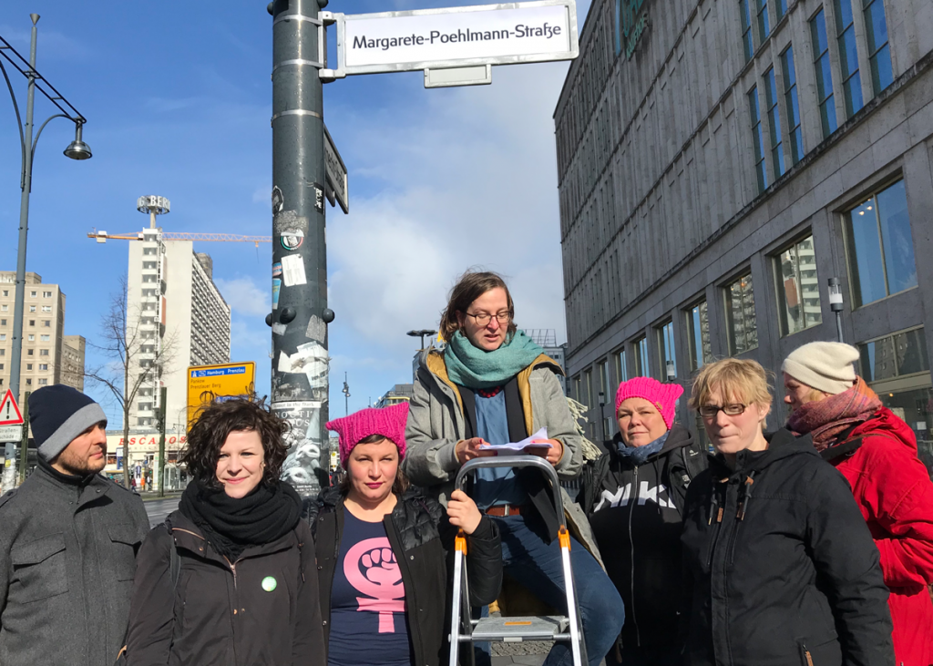 Es sind Silke Gebel, Anja Kofbinger und Antje Kapek am Frauentag in Berlin zu sehen, wie sie ein Straßenschild umbenennen