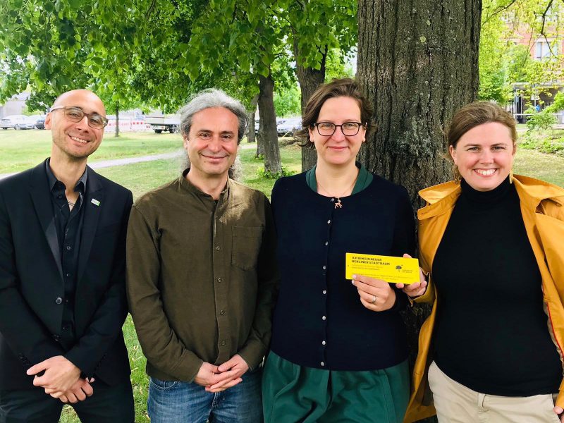 Turgut Altug, Silke Gebel und Clara Herrmann stehen vor einem Baum und freuen sich über den Beschluss zur Berliner Baumpflege