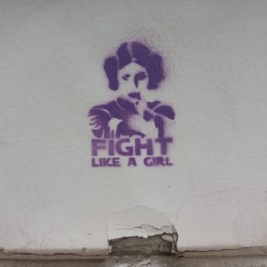 Auf dem Bild sieht man eine Hauswand mit Graffiti, auf dem steht: Fight like a girl.