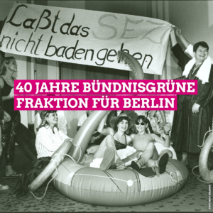 Auf dem Schwarz-Weiß-Bild ist die Grüne Fraktion Berlin zu sehen, die 1994 gegen die Senatspläne zur Privatisierung des Sport- und Erholungszentrum (SEZ) in Friedrichshain protestiert. In der Bildmitte sitzen einige Abgeordnete in Badeklamotten in einer aufblasbaren Schwimminsel. Außerhalb der Insel stehen weitere Abgeordnete die ein Transparent mit der Aufschrift: "Lasst das SEZ nicht baden gehen" in die Höhe halten. In der Bildmitte steht in großen weißen Buchstaben, die pink unterlegt sind, 40 Jahre Bündnisgrüne Fraktion für Berlin.