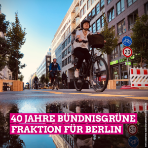 Auf dem quadratischen Bild ist die autofreie Friedrichstraße zu sehen, über die mehrere Leute mit dem Fahrrad fahren. Im vorderen Teil ist eine Pfütze zu sehen, in der sich die Umgebung spiegelt. Auf dem Bild steht außerdem in großer weißer Schrift, die pink unterlegt ist, 40 Jahre Bündnisgrüne Fraktion für Berlin.
