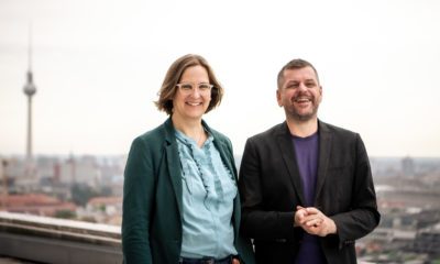 Porträt von Silke Gebel und Werner Graf. Sie sind seriös angezogen und stehen auf einem Berliner Dach, im Hintergrund der Fernsehturm. Beide lächeln in die Kamera.