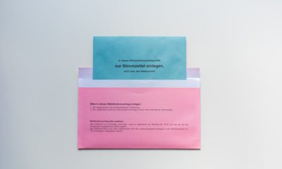 pinker Briefwahlumschlag mit blauem Briefwahlumschlag, der halb darin steckt