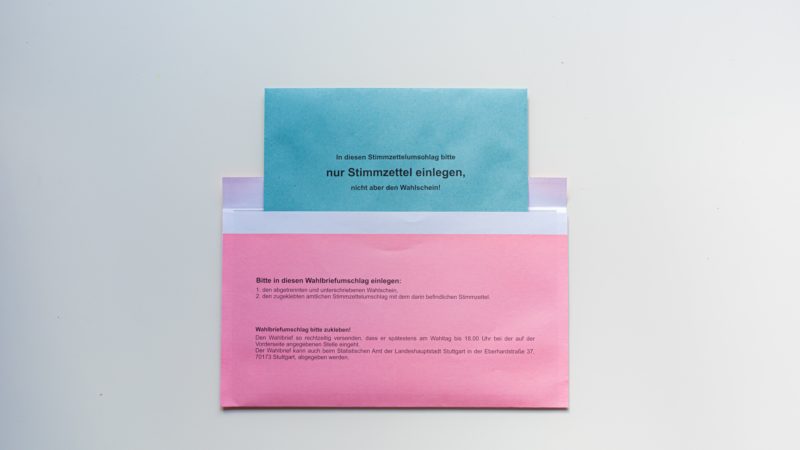 pinker Briefwahlumschlag mit blauem Briefwahlumschlag, der halb darin steckt