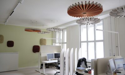 Zu sehen ist ein modernes Büro in einem hellen Raum. Auf einem Schreibtsich stehen zwei Bildschirme, an der Decke hängt eine stilvolle Lampe.