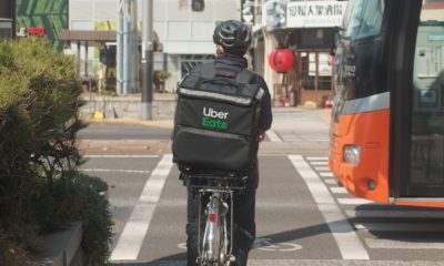 Ein Fahrradfahrer mit einem Rucksack, in dem Essen ausgefliefert wird, fährt auf einem Radstreifen. Von rechts kommt ein Bus angefahren.