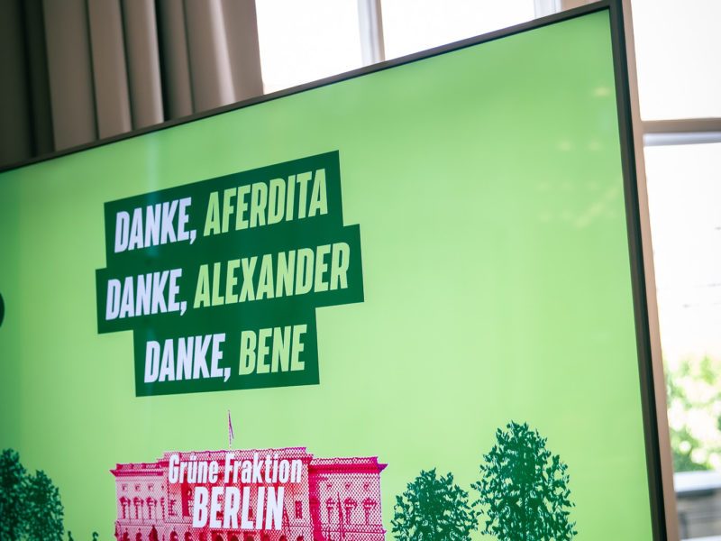 Foto eines Bildschirms, auf dem ein grünes Backdrop zu sehen ist. Darauf der Text: "DANKE, AFERDITA! DANKE, ALEXANDER! DANKE, BENE!"