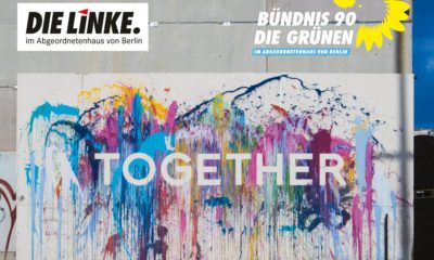 Es ist eine bunt bemalte Wand mit der Aufschrift "together" zu sehen. Darüber stehen die Logos der Grünen und Linken im Abgeordnetenhaus von Berlin
