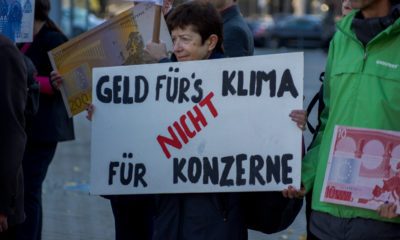 Eine Frau hält ein Demonstrationsschild hoch auf dem steht: "Geld fürs Klima, nicht für Konzerne"