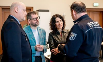 Werner Graf und Bettina Jarasch im Gespräch mit zwei Polizisten in Uniform.